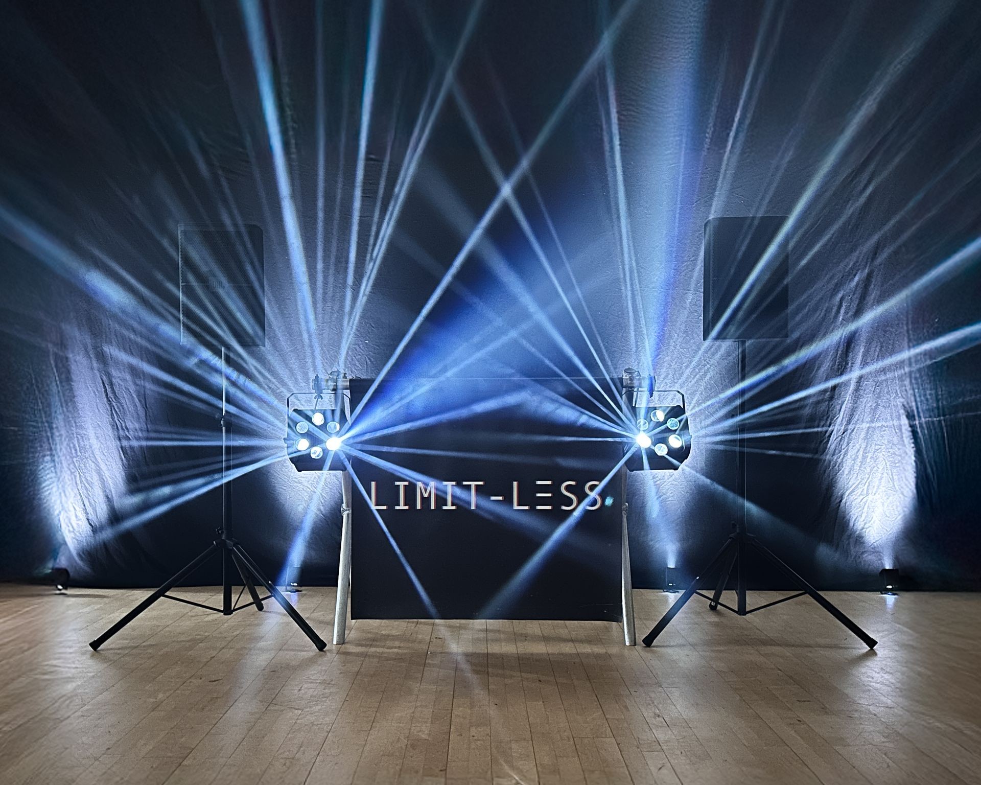 Stage with beams of light, speakers, and 'LIMITLESS' sign in the center.
